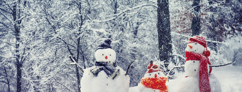 Drei Schneemänner mit Schal im Winter