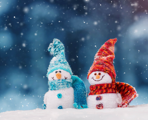 Zwei Schneemänner aus Strick mit Mütze und Schal