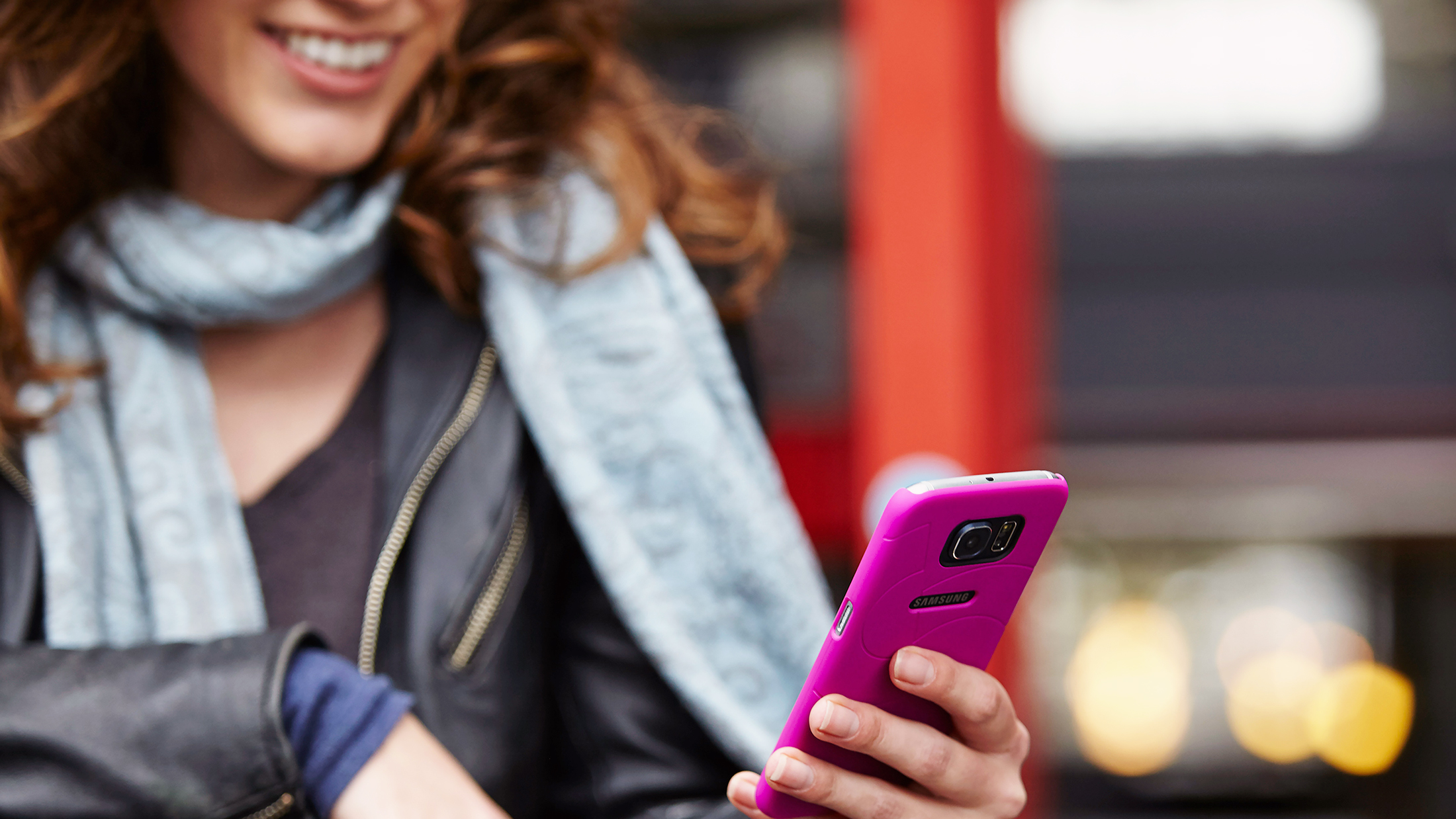 Lächelnde Frau schaut auf ihr pinkes Handy